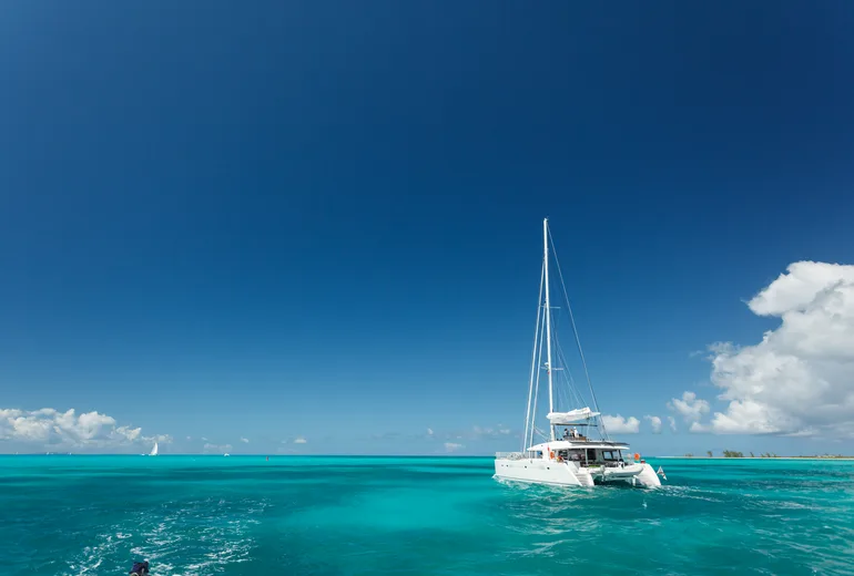 Catamaran cruising turquoise shallows under settled trade winds